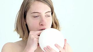 a young babe tries blowing and popping her first balloon in a looner session