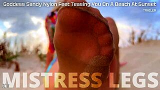 Goddess Sandy teases with nylon feet on beach at sunset.