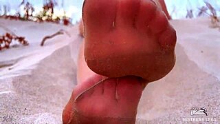 Goddess Sandy teases with nylon feet on beach at sunset.