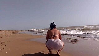 This morena Latina shakes her huge ass wildly while fingering pussy on sunny beach sand!